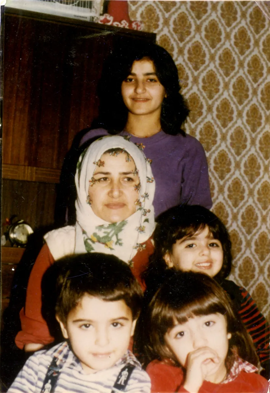 Ein Familienfoto im Wohnzimmer vor der Schrankwand. In der Mitte die Mutter Ferdane Satır und dahinter ihre Tochter Zeliha. Auf ihrem Schoß sitzt die jüngste Tochter Songül und im Vordergrund sind Çiğdem und Ümit.