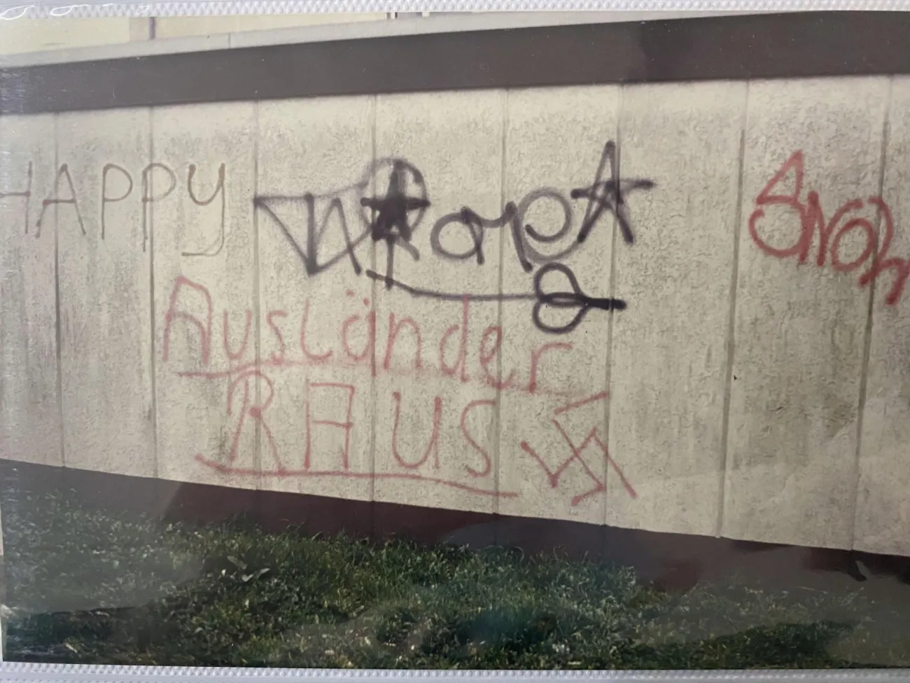 Mehrere Graffiti auf einer Häuserwand, darunter: „Ausländer raus“ und ein Hakenkreuz.