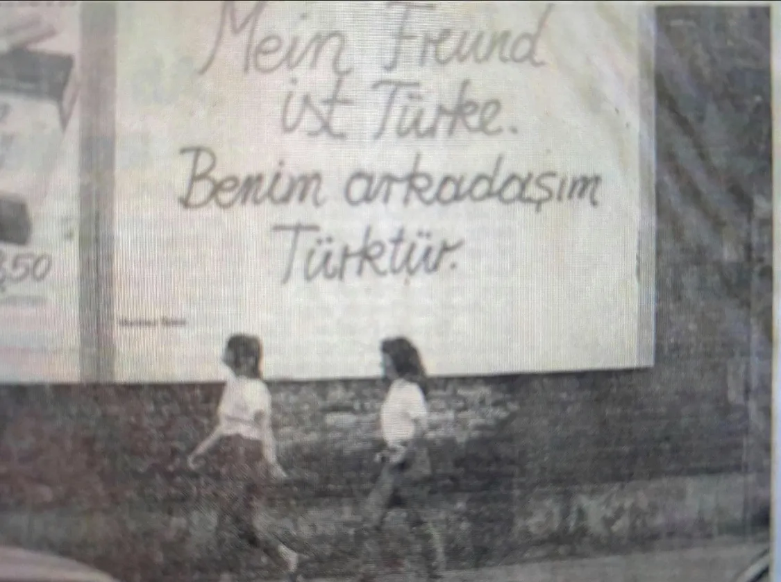 Foto einer Plakatwand. Auf dem Plakat steht in Handschrift: „Mein Freund ist Türke. Benim arkadaşim Türktür.“